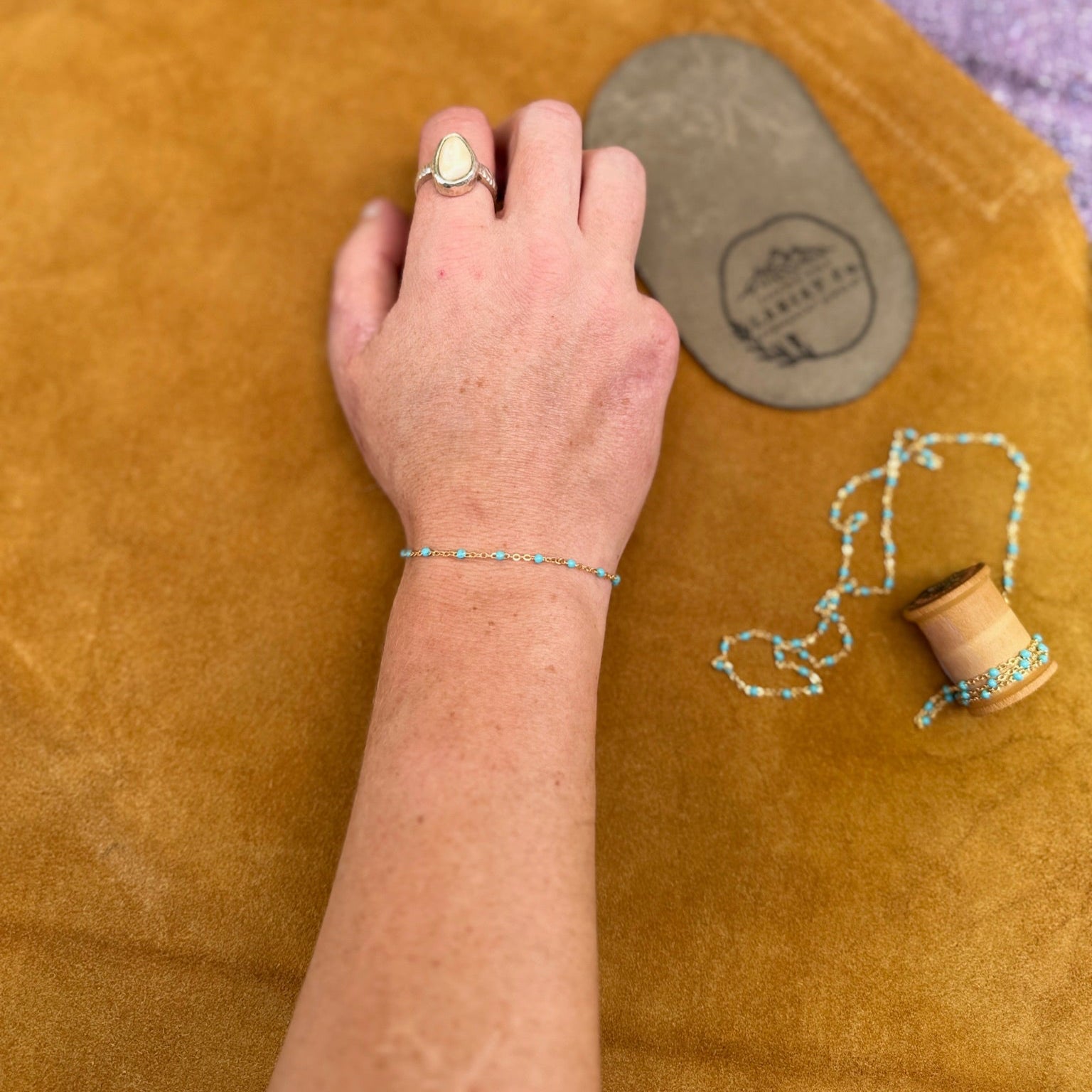 Woman's arm with a Jackson Hole Lariat Co. permanent bracelet with turquoise acrylic beads.