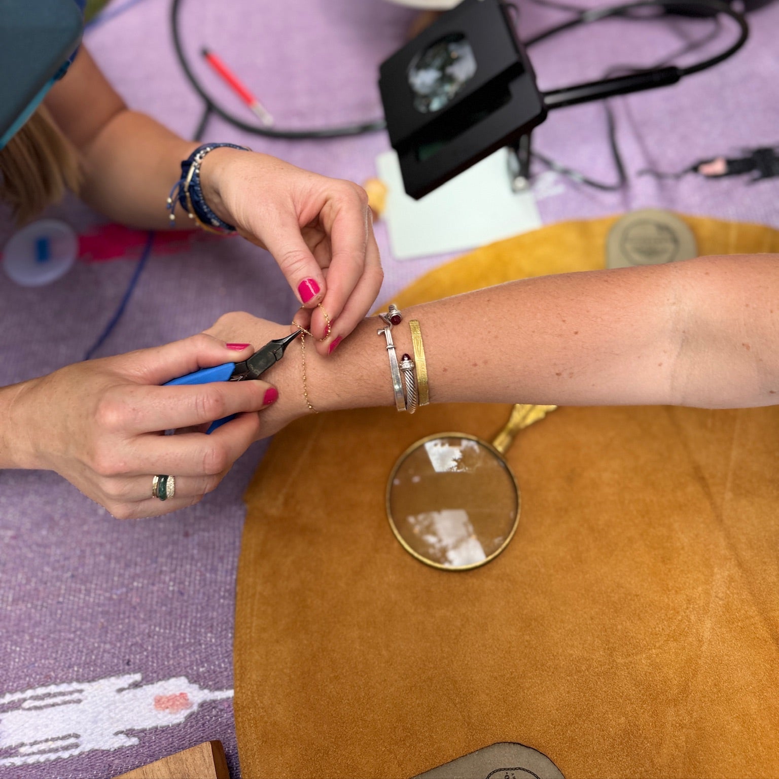Woman sizing a permanent jewelry bracelet on another woman.
